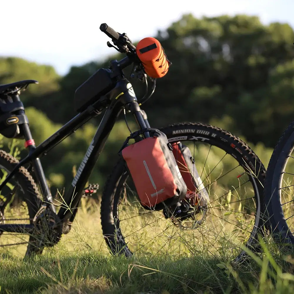 Rhinowalk waterproof bike bag attached to a mountain bike fork in a grassy field.