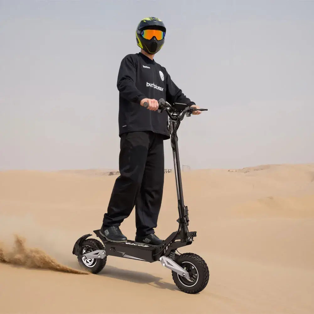 Rider on a 900W Foldable Off-Road Electric Scooter navigating sandy terrain with off-road tires.
